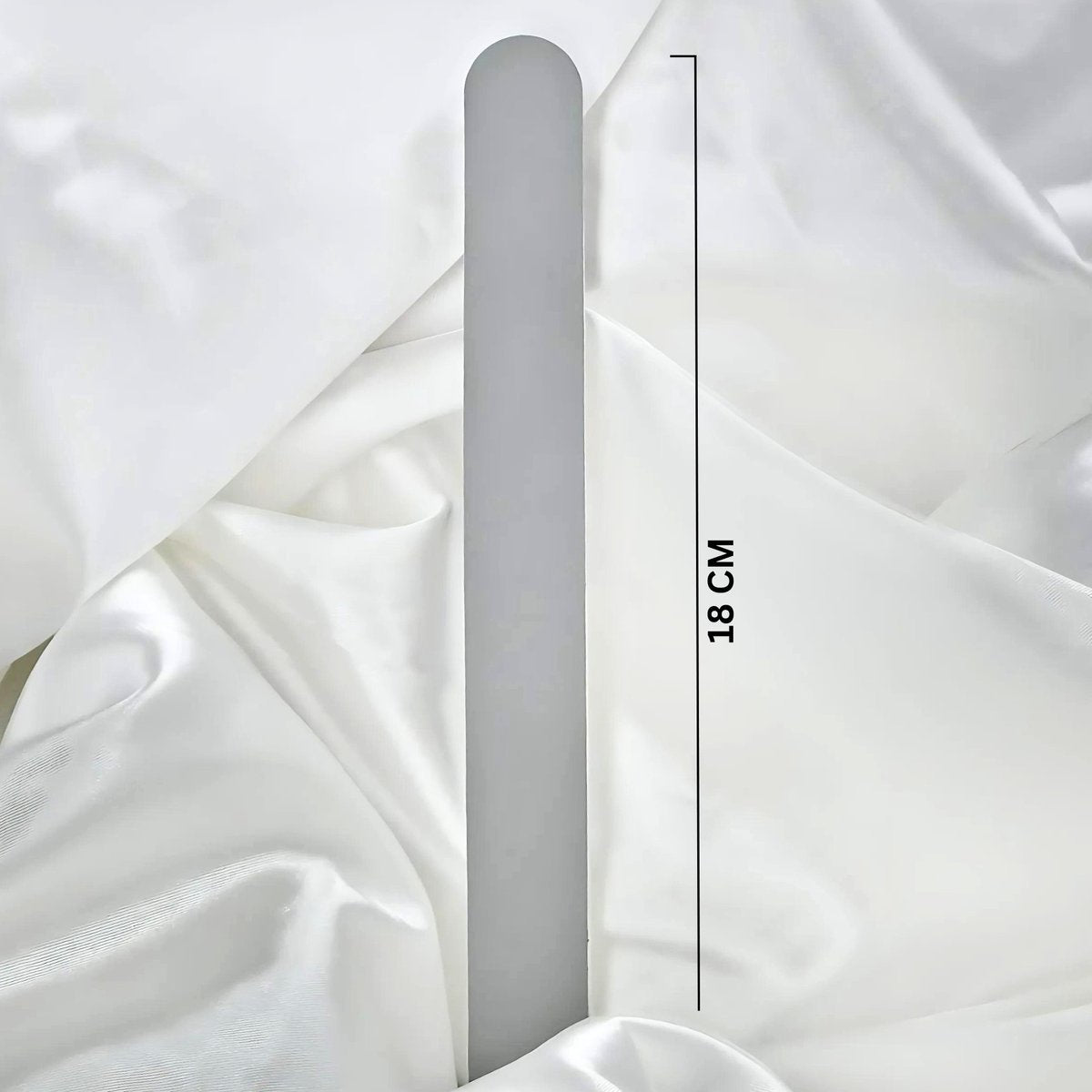 White nail file on a white fabric background with measurement text